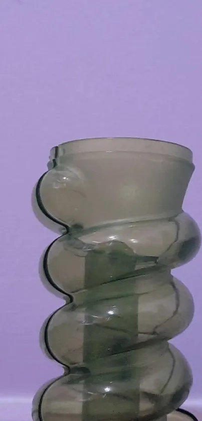 Abstract glass vase against lavender wall.