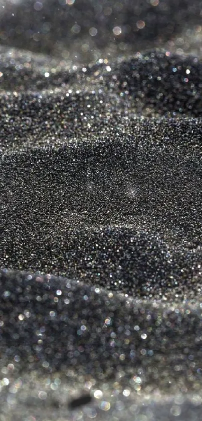 Close-up of glittering black sand texture in an abstract mobile wallpaper.