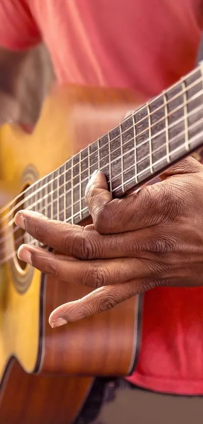 Close-up of hands playing an acoustic guitar on a wallpaper.