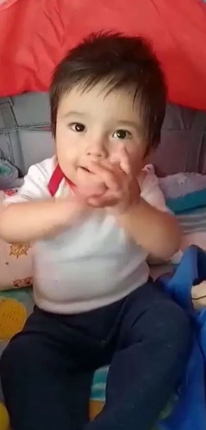 Adorable baby clapping hands in a vibrant and playful setting.