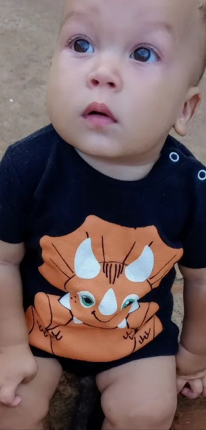 Cute baby in dinosaur outfit sitting outdoors.