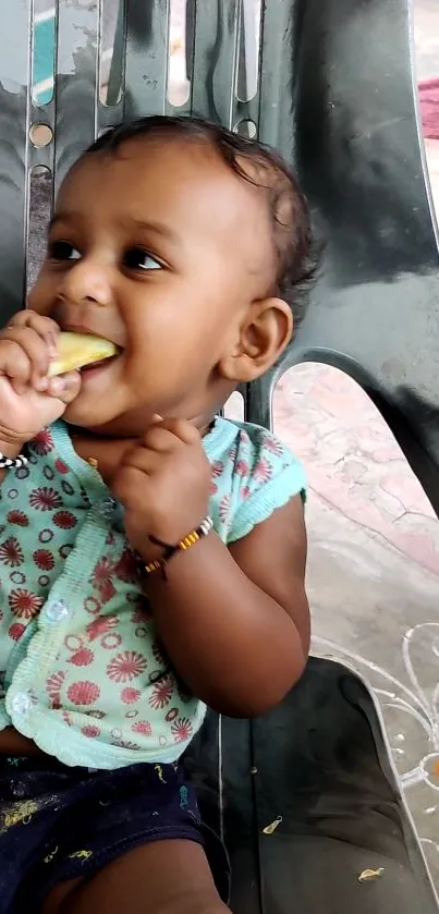 Cute baby eating a fruit while sitting on a chair.