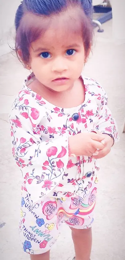 Cute toddler girl in floral outfit standing and looking ahead.