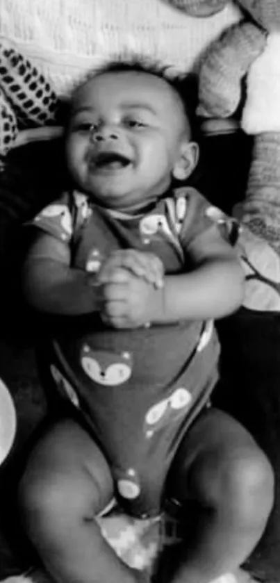 Black and white wallpaper of a smiling baby with plush toys.