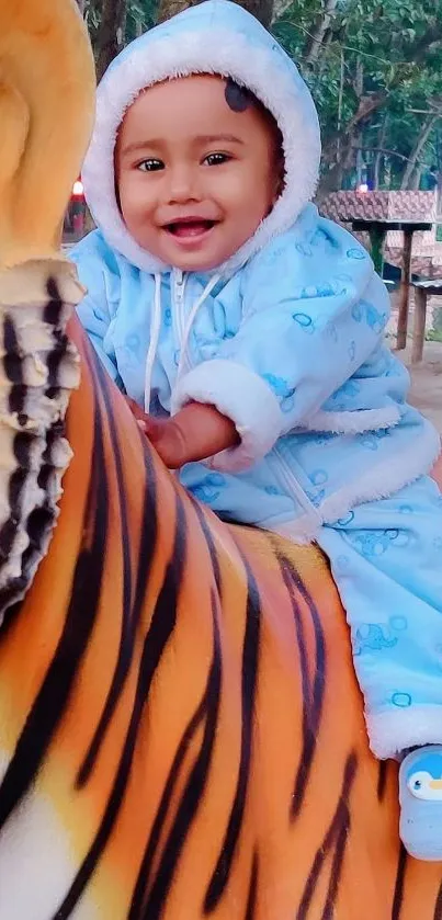 Smiling baby in blue onesie on tiger ride with forest background.