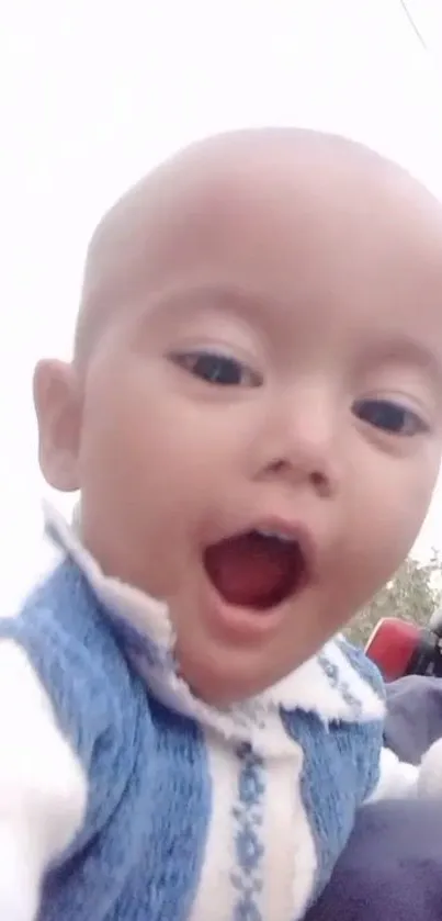 Adorable baby in blue sweater, smiling at the camera.