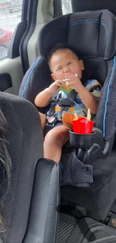 Baby smiling in car seat holding snacks, travel moment.