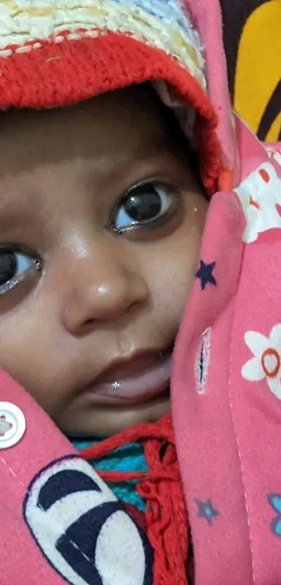 Adorable baby wrapped in a pink floral blanket with wide eyes.