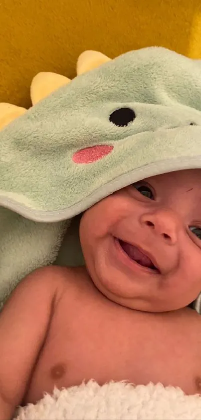 Smiling baby in a cute dinosaur hood with a yellow background.