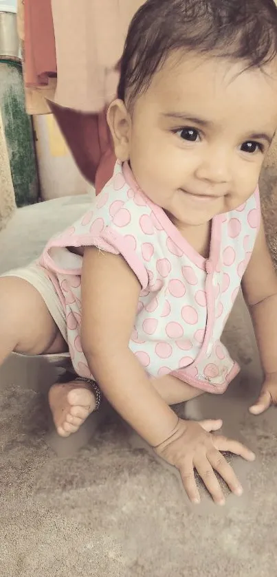 Adorable baby in pink polka-dotted outfit crawling and smiling.