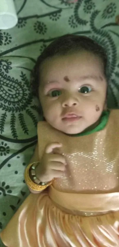 Cute baby in peach outfit with paisley background.