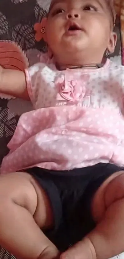 Smiling baby in pink dress lying down