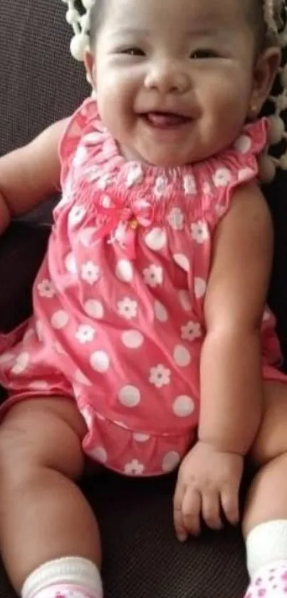 Adorable baby smiling in a pink dress.