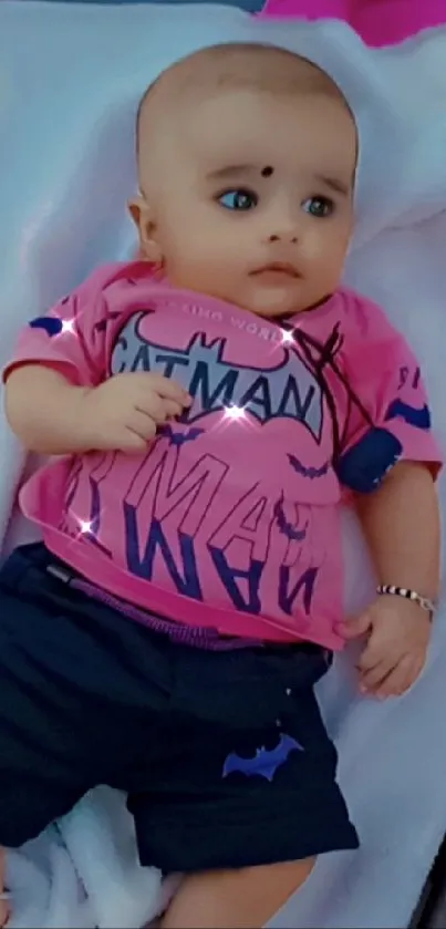 Adorable baby in pink shirt and blue shorts on soft background.