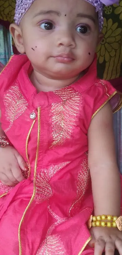 Adorable baby in a pink outfit with purple accessories.