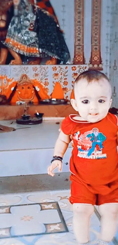 Adorable baby in red outfit stands in colorful temple.