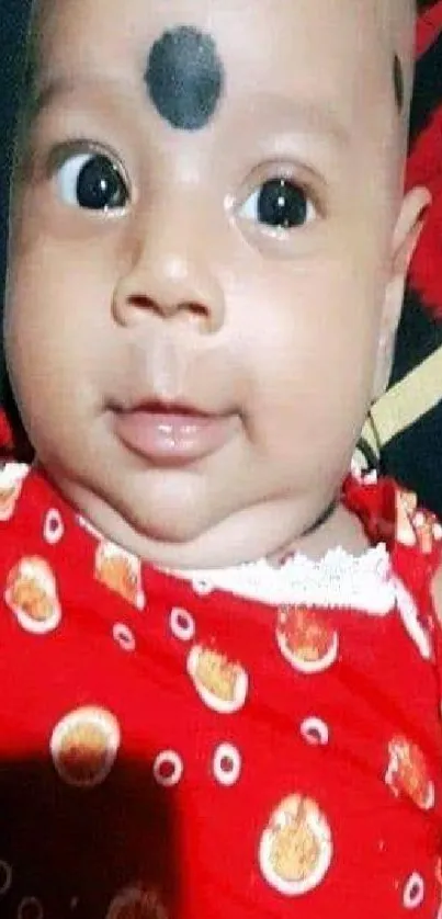 Cute baby smiling in red patterned outfit.