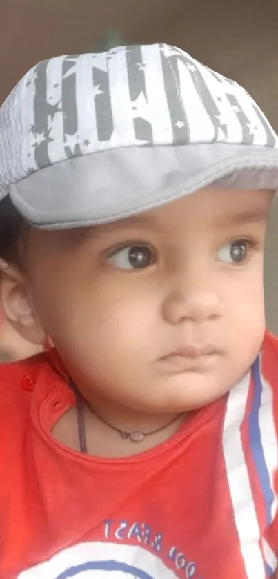 Adorable baby in red shirt with cap.