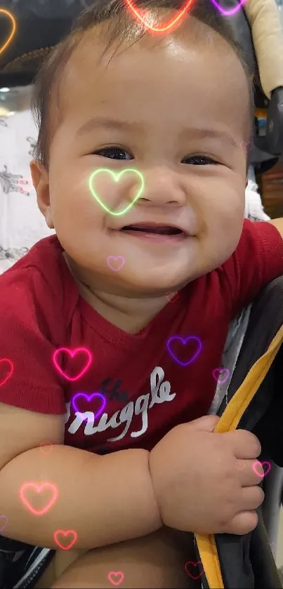 Smiling baby sitting in stroller with red shirt.