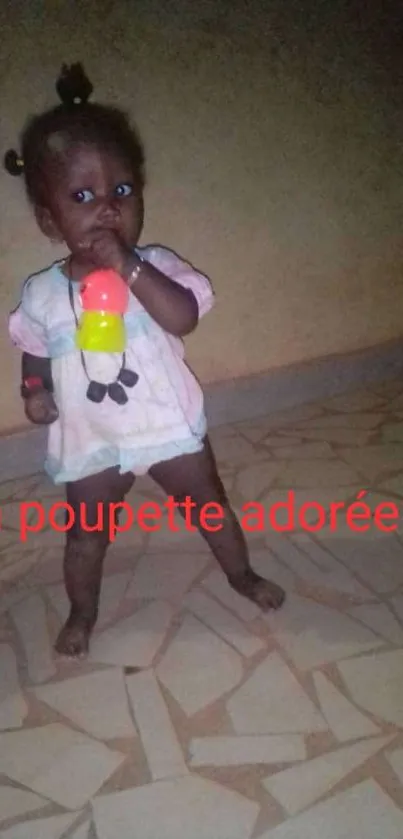 Adorable baby standing on a patterned floor with a vibrant toy.