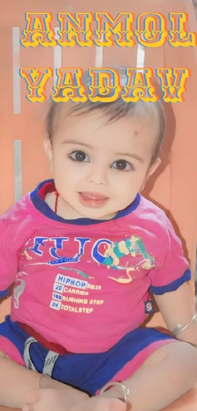 Adorable baby sitting in a colorful outfit with a sweet smile on an orange chair.