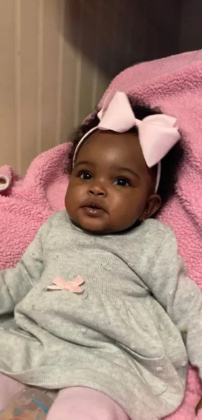 Adorable baby girl with pink bow on blanket.