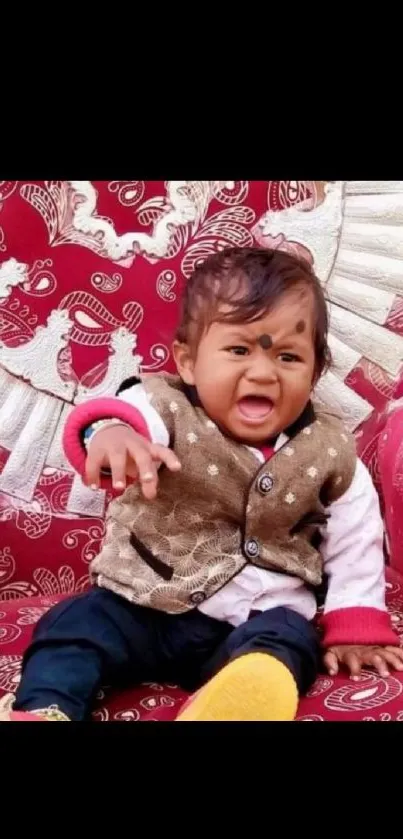 Cute baby smiling on a red patterned chair.