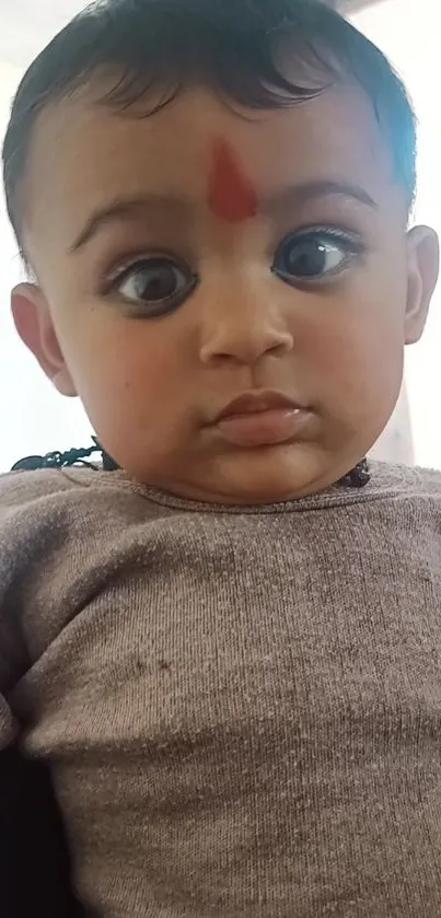 Adorable baby with expressive eyes and soft tone background.