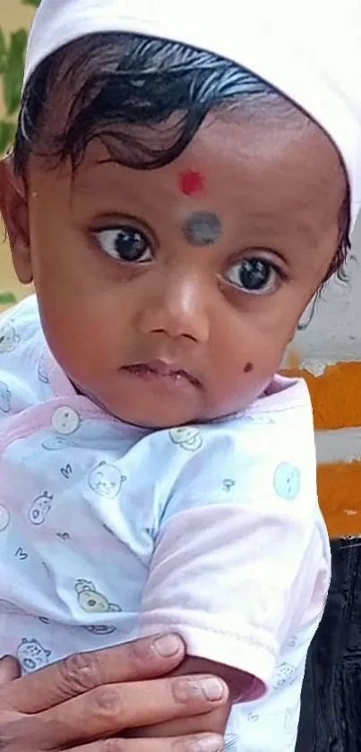 Adorable baby with white cap and colorful background.