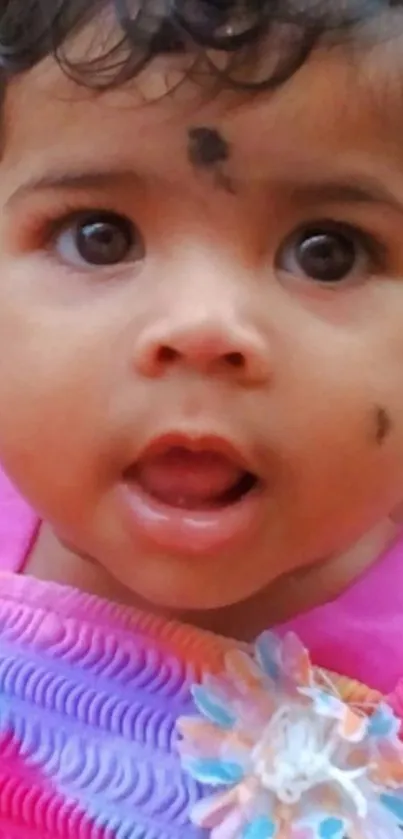 Adorable baby with expressive eyes in a colorful outfit.