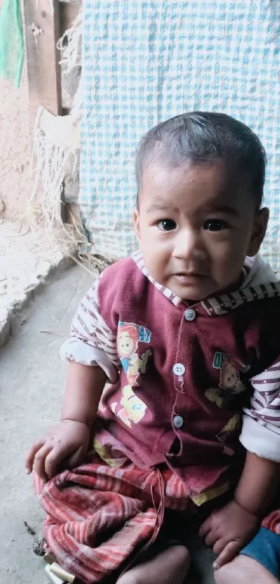 Adorable baby sitting with a charming expression in a warm setting.