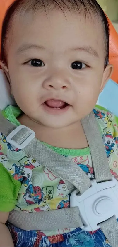 Adorable baby smiling with colorful shirt in stroller.