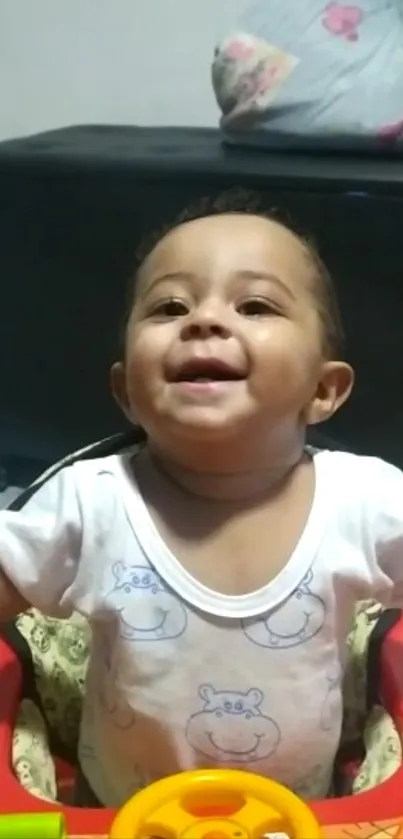 Smiling baby in colorful walker with beige background.