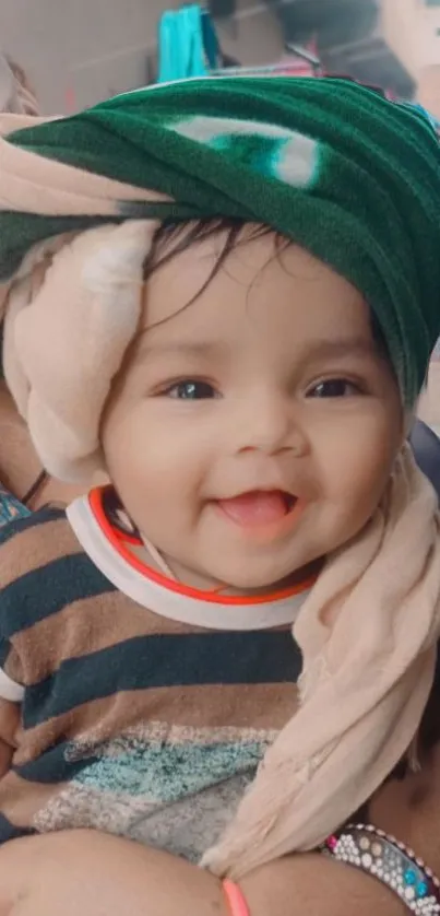 Smiling baby in striped shirt with a green blanket wrapped around.