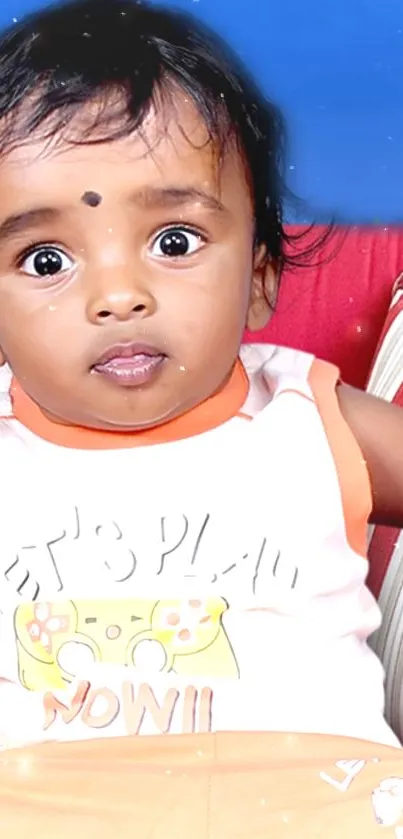 Adorable baby with big eyes on blue sofa.