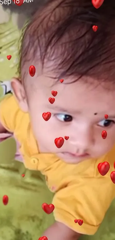 Baby in yellow shirt with animated hearts.