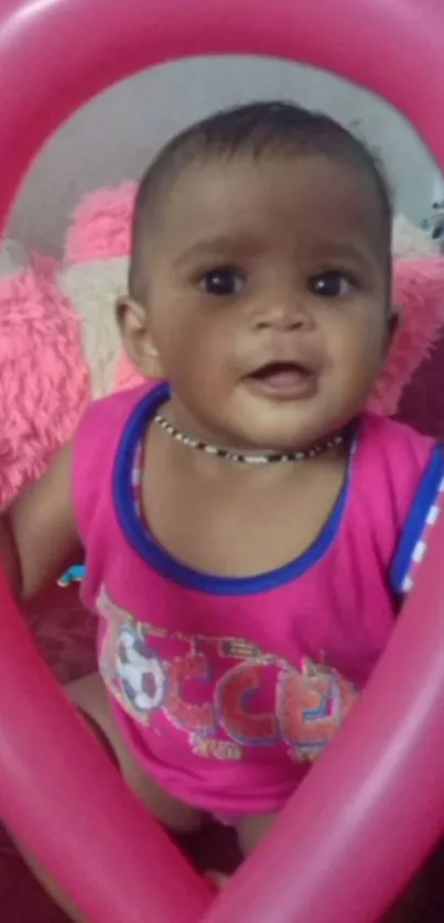 Adorable baby with a pink balloon, smiling happily.