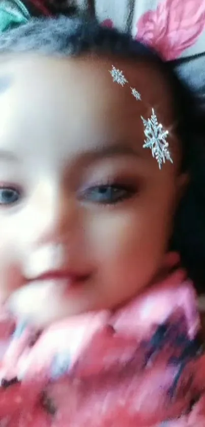 A smiling baby with snowflake decorations on a pink outfit.