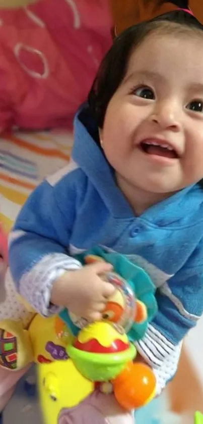 Adorable baby in blue smiling with toys.