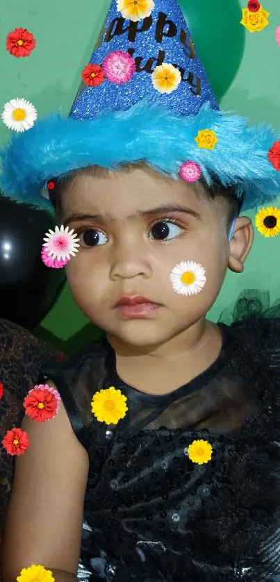 Child wearing a blue birthday hat with green background.