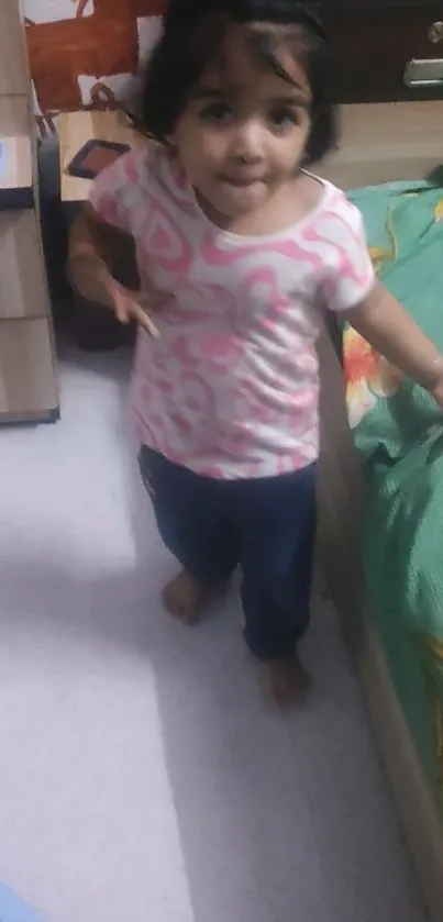 A little girl standing beside a bed in a cozy bedroom.