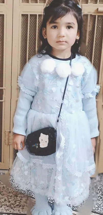 Young girl in a blue lace dress standing indoors.