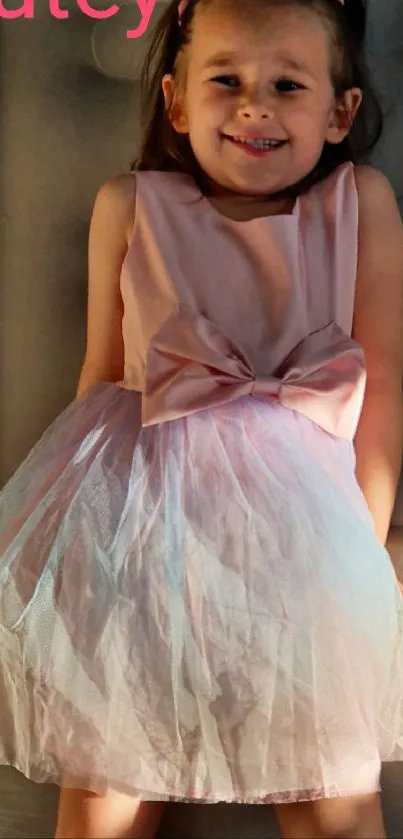 Young girl smiling in a pink dress with a beautiful bow.