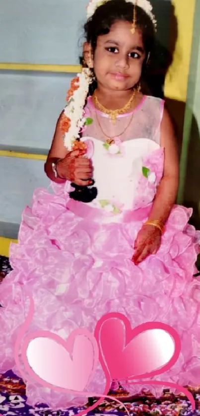 Adorable young girl in a pink dress with heart decor.