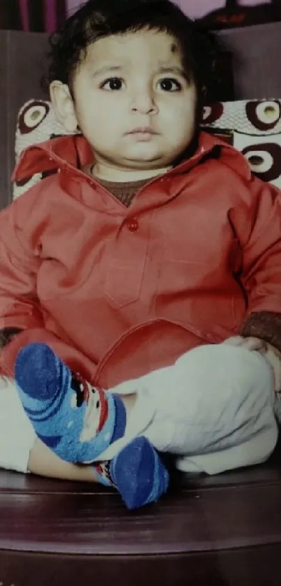 Adorable child in red outfit sitting on a chair.