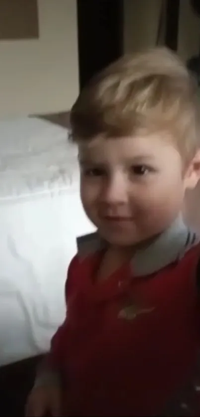 Adorable child in a red shirt smiling indoors.