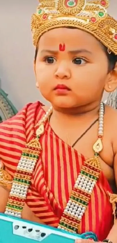 Adorable child in red traditional attire with a crown.