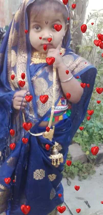 Little girl in a blue saree with gold patterns, standing outdoors.