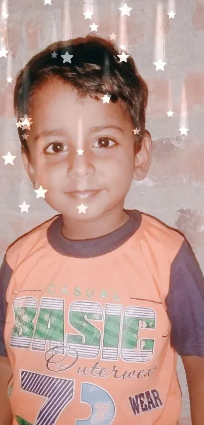 Smiling child in orange shirt against brick wall.