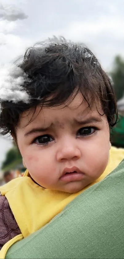 Adorable child held by family in outdoor setting.